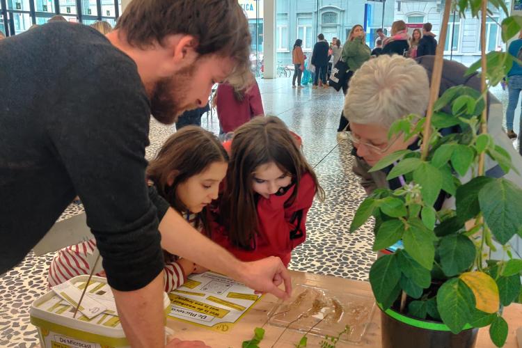 Arne Temmerman giving an explanation about nodules to 2 kids and an older woman. 